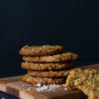 A stack of chewy Anzac biscuits on a wooden board.