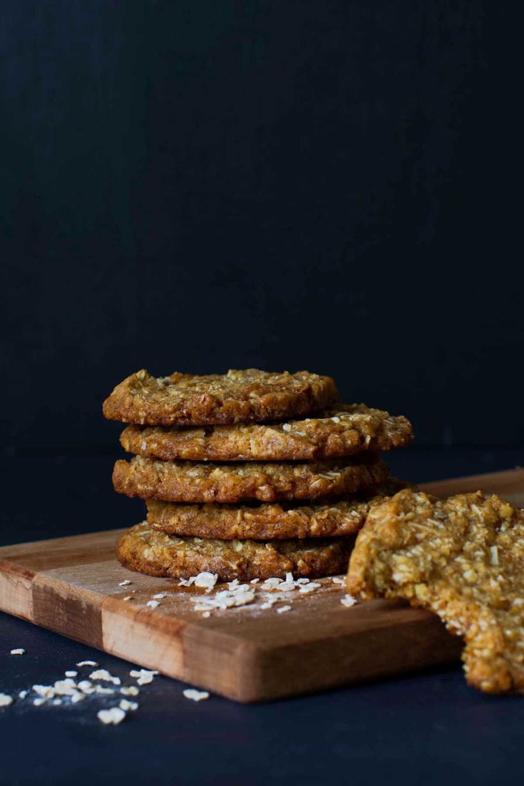A stack of Chewy Anzac Biscuits on a wooden board