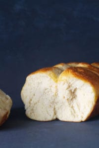 A sourdough brioche loaf that's been cut showing a fluffy inner texture. Dark background.