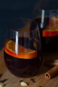 Two glasses of non-alcoholic mulled wine with orange slices in it. Moody scene.