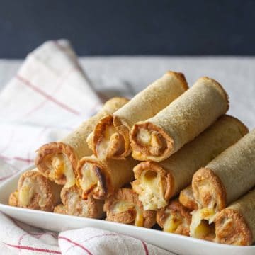 A stack of cheese rolls on a white plate.